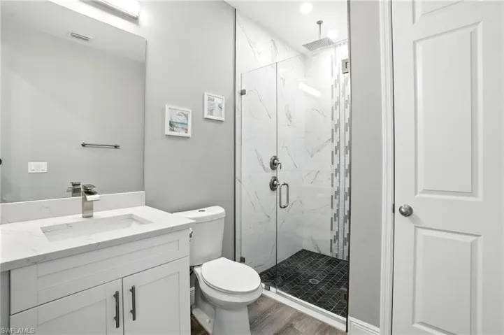 Bathroom featuring a marble finish shower, vanity, and wood finished floors