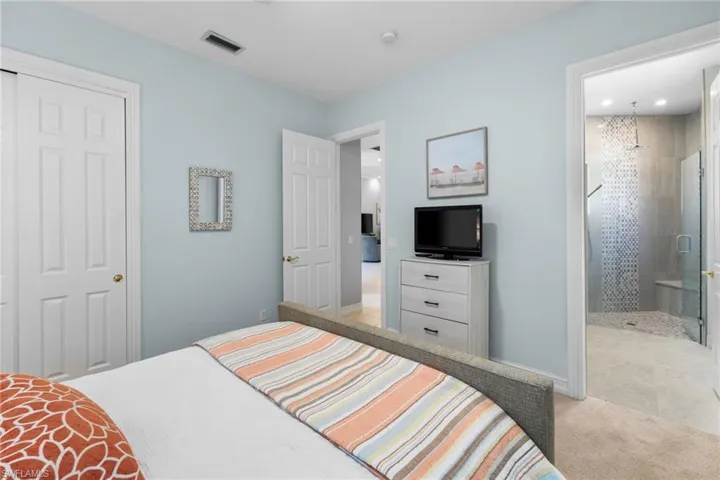 Bedroom featuring a closet, light colored carpet, and ensuite bath