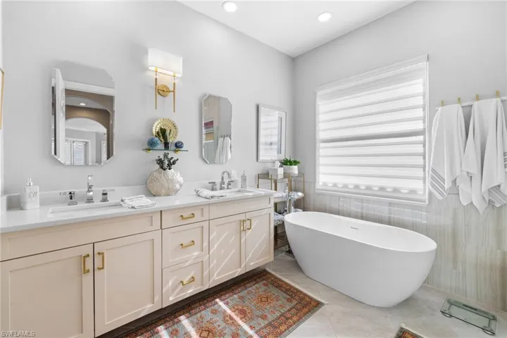 Bathroom featuring tile patterned flooring, vanity, tile walls, and a tub