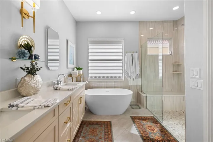 Bathroom featuring shower with separate bathtub, vanity, and tile patterned floors