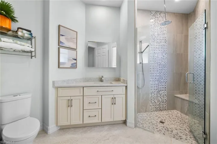 Bathroom with tile patterned flooring, vanity, toilet, and a shower with door