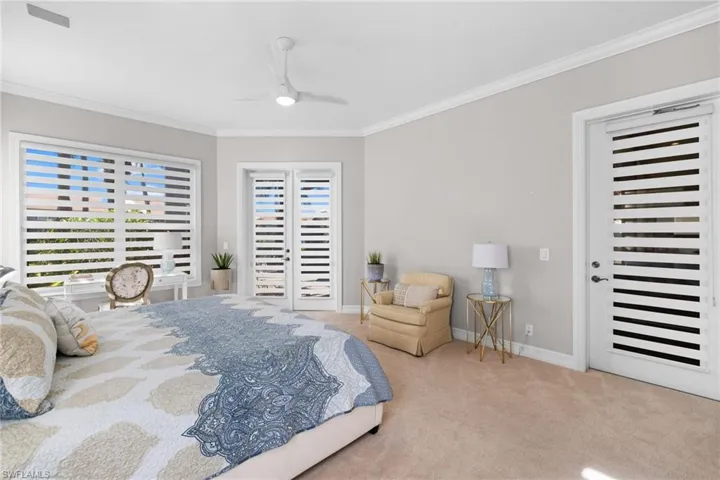Carpeted bedroom with multiple windows, ceiling fan, and crown molding