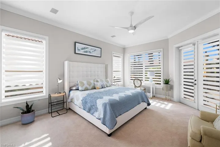 Bedroom with ceiling fan, crown molding, and light carpet