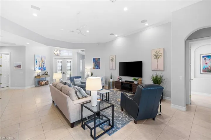 Tiled living room featuring ceiling fan, ornamental molding, and french doors