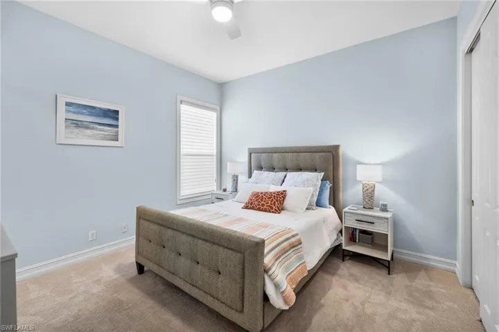 Carpeted bedroom with ceiling fan and a closet