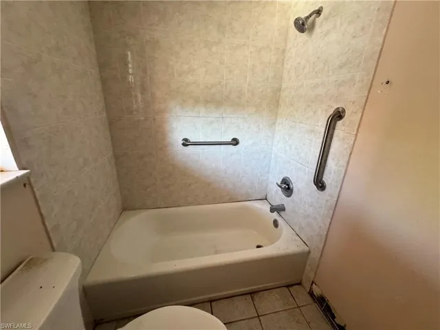 Bathroom with light tile patterned floors and bathing tub / shower combination