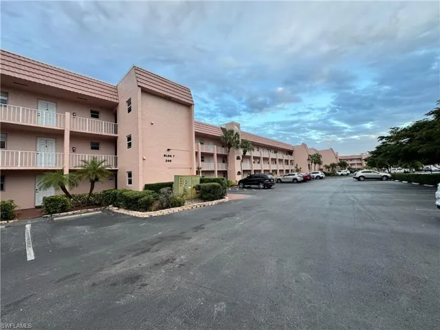 View of apartment building / complex featuring uncovered parking