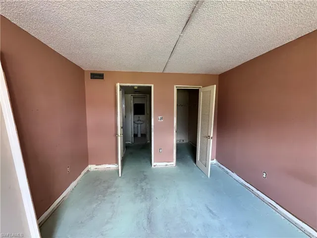 Unfurnished bedroom featuring a textured ceiling, concrete floors, and a spacious closet