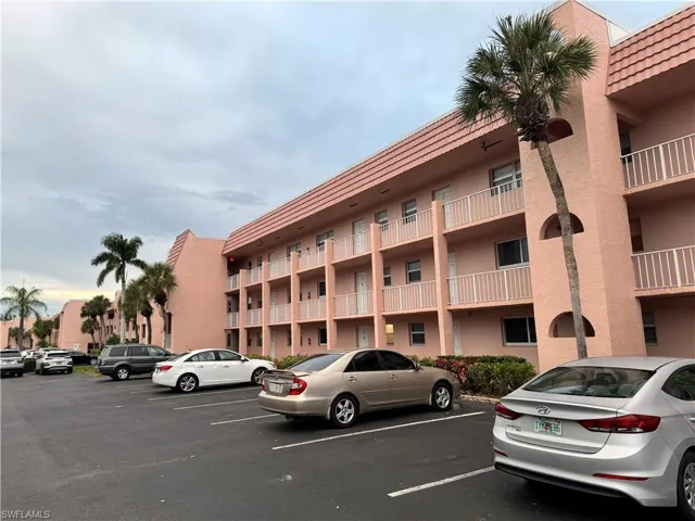 View of apartment building / complex featuring uncovered parking