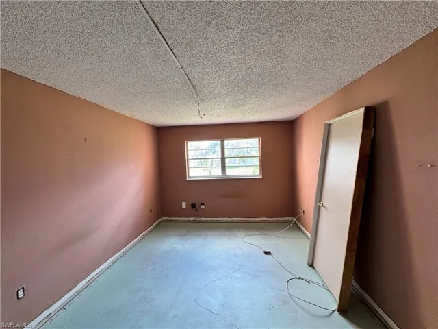 Empty room featuring unfinished concrete floors and a textured ceiling