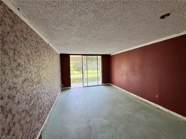 Empty room with expansive windows, unfinished concrete flooring, and a textured ceiling