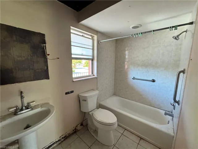 Bathroom with light tile patterned floors and  shower combination