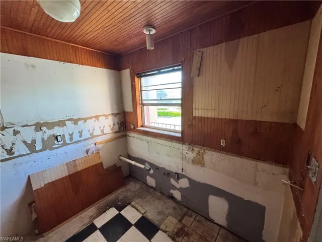 Bathroom with tile patterned floors, wood walls, and wooden ceiling
