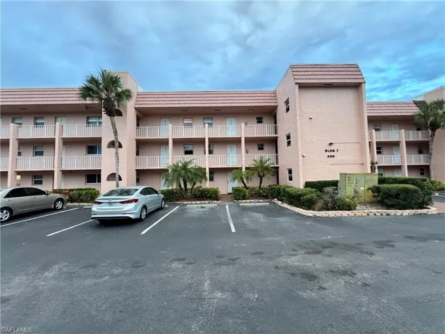 View of apartment building / complex featuring uncovered parking