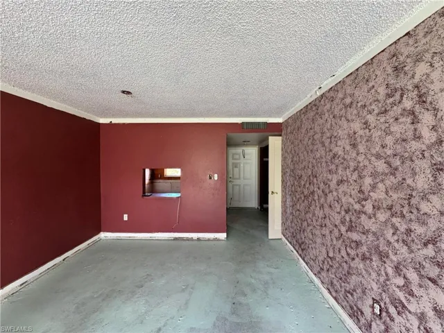 Empty room with concrete floors, ornamental molding, and a textured ceiling