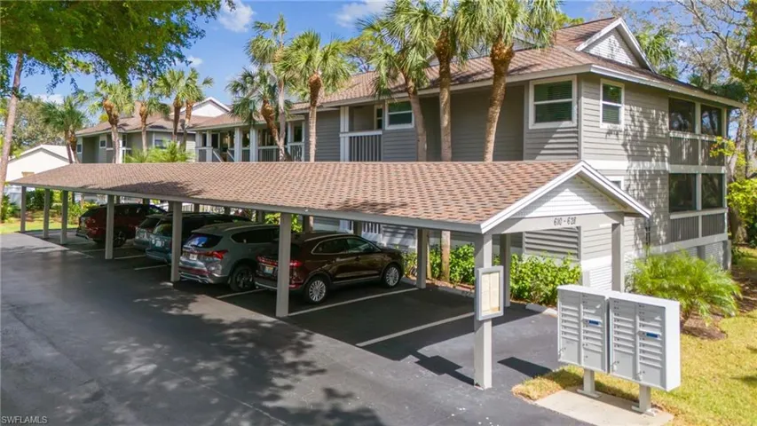 View of parking / parking lot with mail boxes and a carport