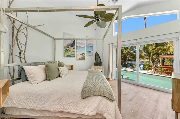 Bedroom featuring light wood finished floors, access to exterior, lofted ceiling, ceiling fan, and a water view
