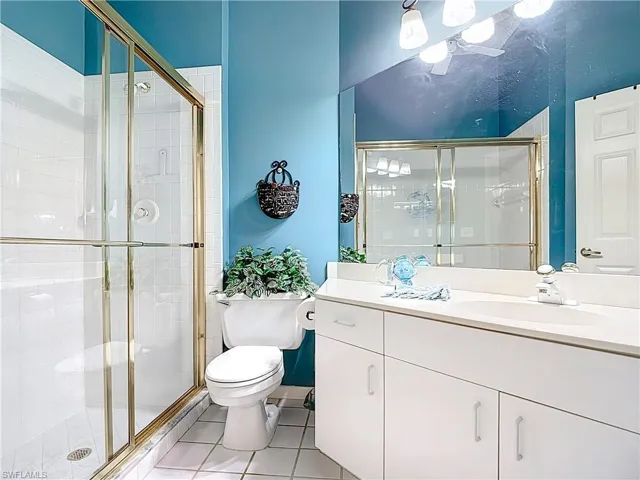 Full bath with tile patterned floors, vanity, a shower stall, and toilet