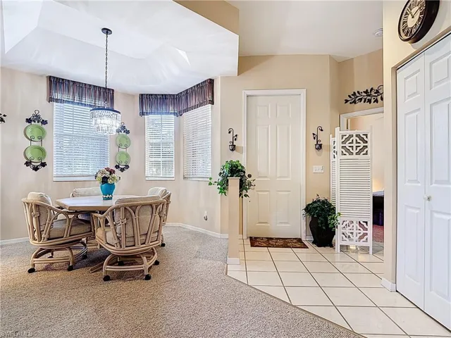 Dining space with an inviting chandelier, light tile patterned floors, baseboards, and light carpet