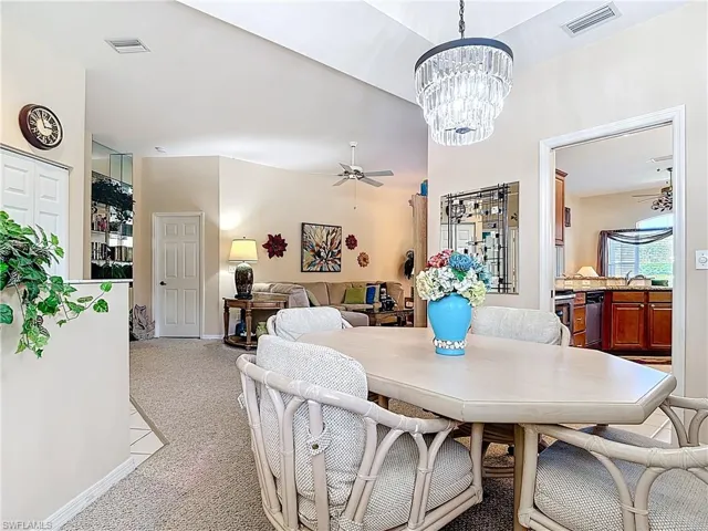 Dining room with ceiling fan with notable chandelier, visible vents, carpet floors, and baseboards