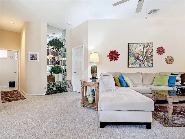 Carpeted living room with visible vents, baseboards, and a ceiling fan
