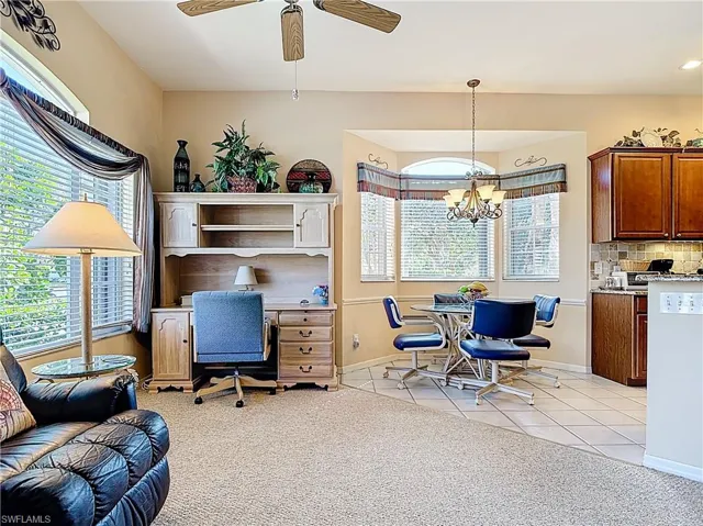 Home office featuring light tile patterned flooring, ceiling fan with notable chandelier, and baseboards