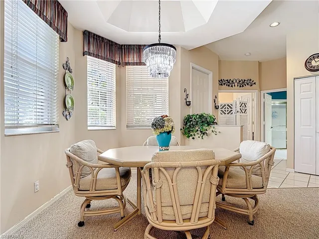 Dining room featuring light tile patterned floors, baseboards, an inviting chandelier, recessed lighting, and a raised ceiling