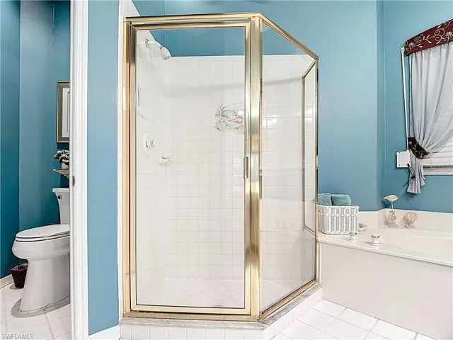 Bathroom featuring a shower stall, toilet, and tile patterned floors