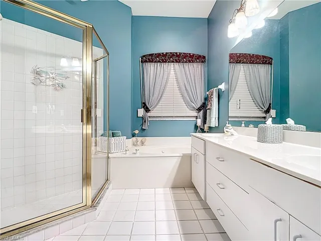 Full bathroom featuring a bath, a shower stall, tile patterned floors, and vanity