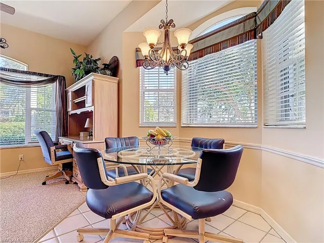 Carpeted dining space with a wealth of natural light, a chandelier, and tile patterned flooring