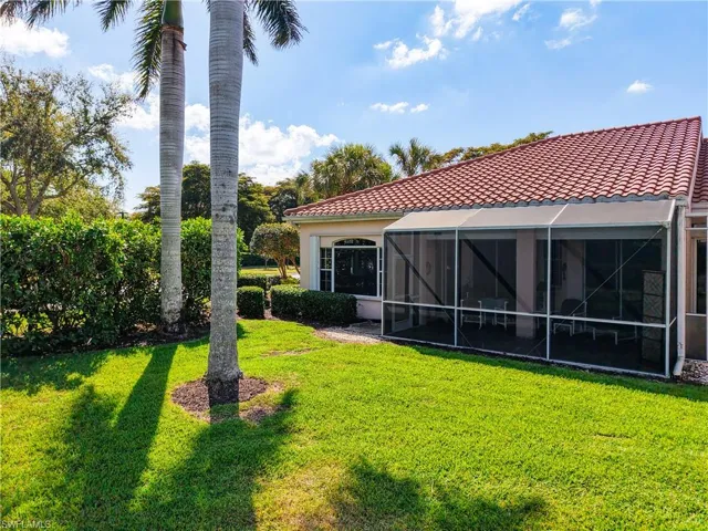 Back of property with a yard, a lanai, and a tile roof