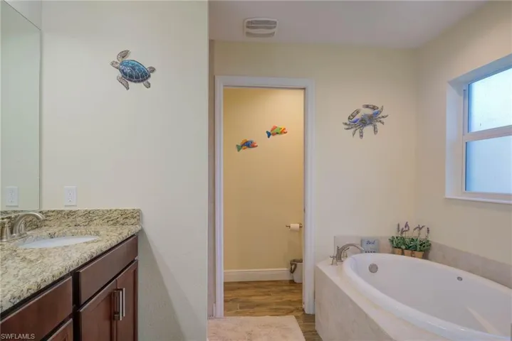 Bathroom with a relaxing tiled tub, vanity, and hardwood / wood-style flooring