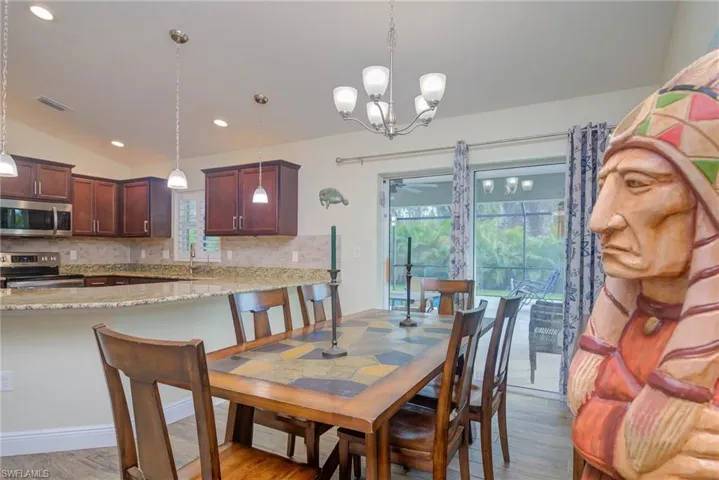Dining space with light hardwood / wood-style floors, vaulted ceiling, and a wealth of natural light