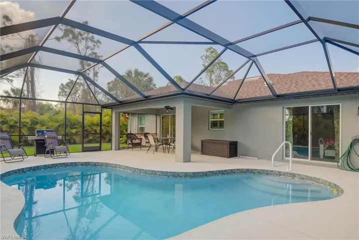 View of pool with a patio, ceiling fan, and glass enclosure