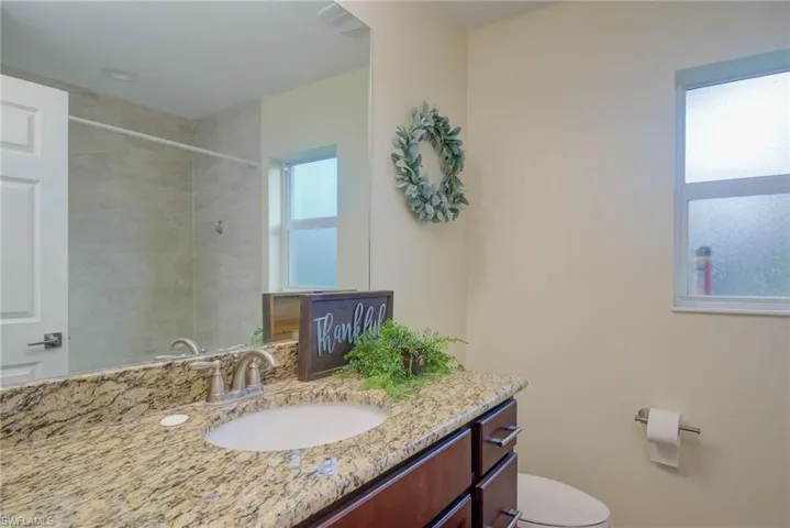 Bathroom with vanity, tiled shower, and toilet