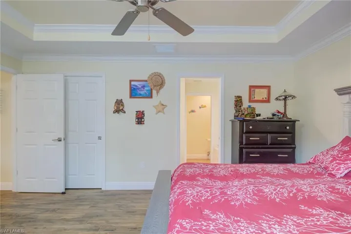 Bedroom featuring crown molding, ceiling fan, hardwood / wood-style floors, connected bathroom, and a raised ceiling