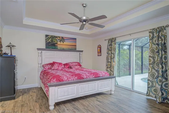 Bedroom with a raised ceiling, wood-type flooring, access to outside, and crown molding