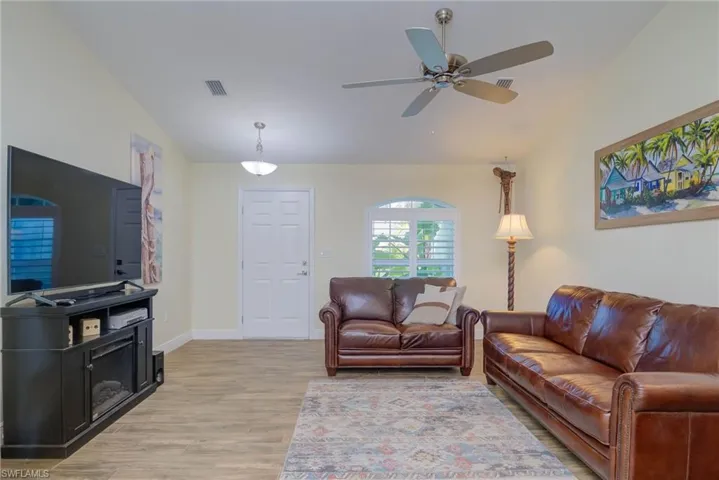 Living room with vaulted ceiling, ceiling fan, and hardwood / wood-style floors
