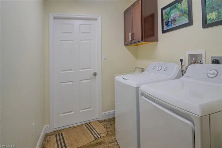 Laundry area featuring hardwood / wood-style floors, washer and clothes dryer, and cabinets