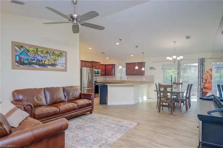 Living room featuring sink, ceiling fan with notable chandelier, and light hardwood / wood-style flooring