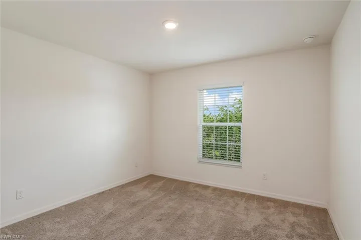 Carpeted room featuring a single window with blinds, recessed ceiling lighting, and a neutral wall palette