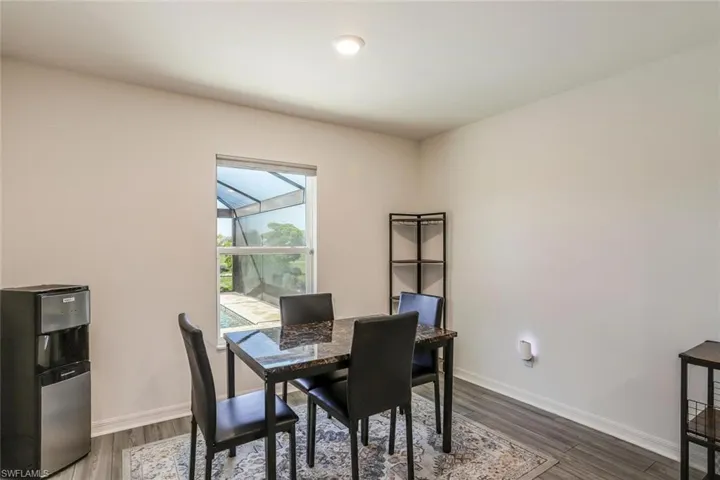 Interior room featuring a single window overlooking a screened-in pool area, wood-finish flooring, and light-toned walls