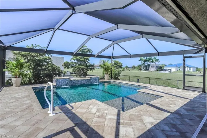 Screened lanai featuring a swimming pool with a stone-clad waterfall and integrated spa