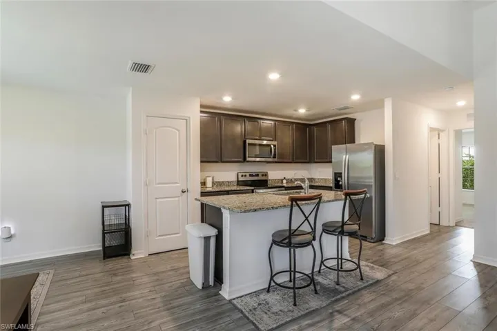 Kitchen featuring dark wood-finish cabinetry, stainless steel appliances, and a granite countertop island with seating
