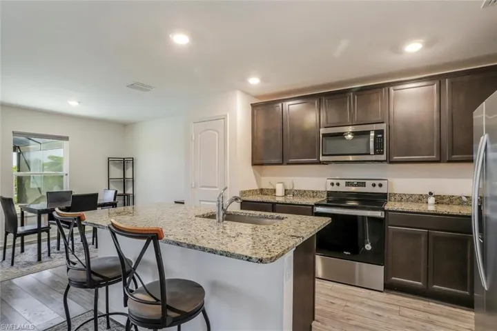 Kitchen featuring dark wood cabinetry, stainless steel appliances, and granite countertops