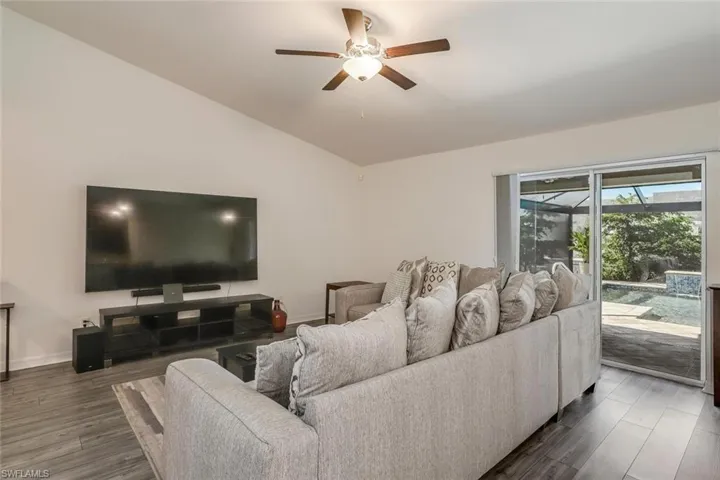 Spacious living area featuring vaulted ceilings, wood-finish flooring, and a ceiling fan with integrated lighting