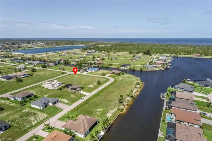 Aerial perspective showcasing a residential development with waterways and open land