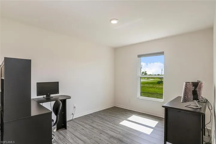 Bright interior space featuring wood-finish flooring, white walls, and a single window with a wide sill