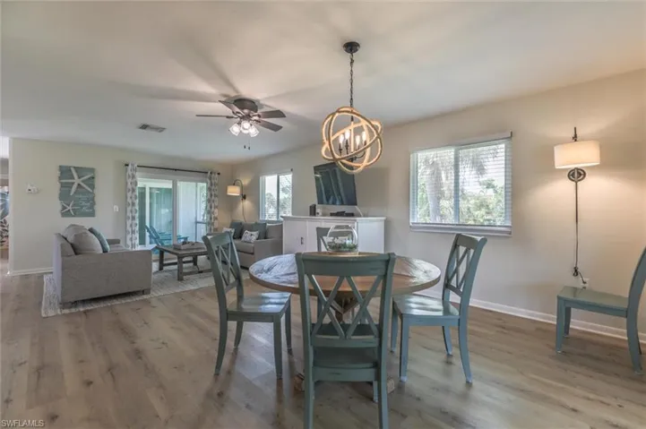 Dining space with hardwood / wood-style flooring, ceiling fan with notable chandelier, and a healthy amount of sunlight