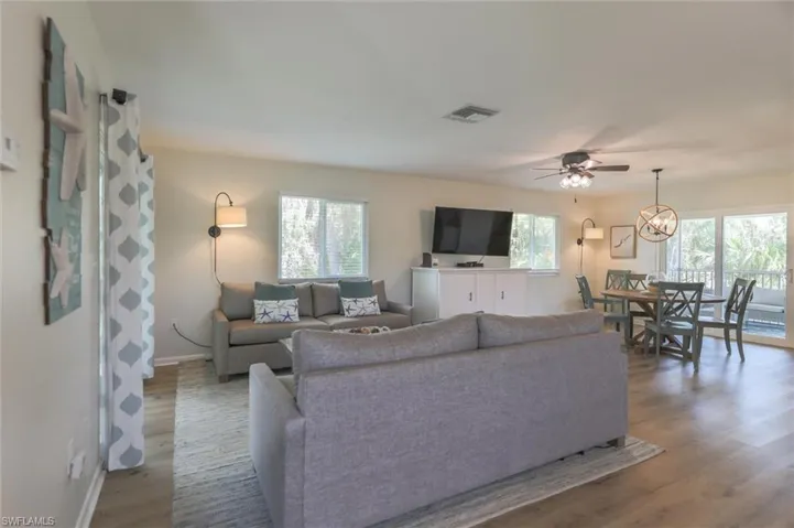 Living room featuring a healthy amount of sunlight, ceiling fan with notable chandelier, and wood-type flooring